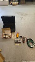 Lot of electrician tools laid out on floor with carrying case and various meters and tools