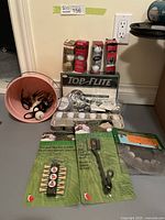 Overview of golf balls and accessories on the floor including pink bucket with golf balls, golf tees and Top-Flite boxed balls
