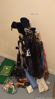 Photo showing full golf set with clubs, Bag Boy cart, umbrellas, golf balls, tees, hand weights, yoga mat, and table tennis paddles.