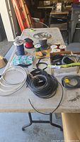 Wide view showing various wire spools, cables, and electrical accessories on a table in a garage setting.