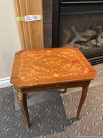 Music box table showing full front and side view with carved legs and inlaid floral patterns