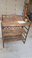 Front view of wooden 3-shelf potting bench showing lattice back and slatted shelves.