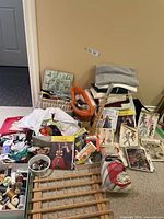 Full view of sewing notions, patterns, fabric blocks, and wooden thread rack on floor against wall