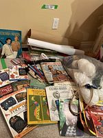 Overview of craft books, magazines, yarn, and craft tools arranged on floor.