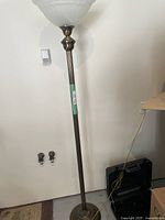 Full view of the tall brass floor lamp showing the straight pole base and the power cord, illustrating the lamp's height and slim profile.