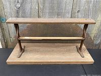 Full view of the antique country store paper roll dispenser showing the wooden base and ornate cast iron brackets from front.