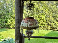 Front view of antique hanging parlor lamp showing hand-painted glass shade with berries and clover leaves, brass filigree trim, and hanging crystal prisms.