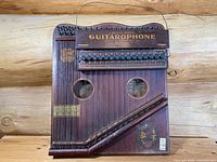 Full view of front face showing push-button chord bar, strings, soundholes and decal artwork