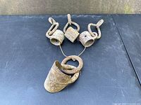 Four antique, hand-forged iron truss hardware pieces laid out on a black surface showing rusty, primitive finish and structural details.