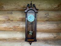 Front view of the Vienna regulator wall clock showing wooden carved case and visible dial and pendulum.