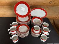 Full set displayed on black surface with all pieces grouped: plates, bowls, cups, saucers, and platter visible.