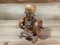 Front side view of the wooden model Hit & Miss engine showing flywheels, piston mechanism, and fuel tank detail on a wooden base