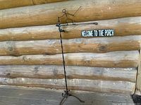 Full view of the metal bracket with stick figure and wooden sign against log wall