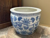 Side view of the blue and white ceramic fish bowl planter showing hand-painted floral grapevine pattern and decorative border near rim.