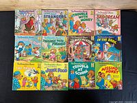Top-down view of all 12 Berenstain Bears books from the First Time Readers series laid out on a dark surface, showing cover art and titles distinctly.