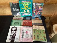 Overview of entire lot arranged on table, showing all 14 vintage piano and vocal sheet music books including Beatles Forever, Reader's Digest 100 Hits, Disney Favorites, Hanon exercises, Man of La Mancha selections, Christmas with the King Family among others.
