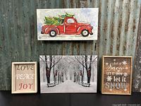 Group photo showing all four pieces of holiday wall décor including red truck canvas, winter park scene, Let it Snow plaque, and Love, Peace, Joy plaque.