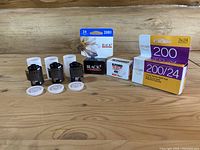 Photo of multiple 35mm film rolls and boxes, showing Black's 200 ISO, Ilford 40 ISO, and Easypix 200 ISO triple pack
