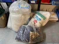 Full lot showing multiple packages of white quilt batting, large roll of polyester fill, and a bag of assorted fabric pieces.