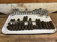 Wide view of deep impact sockets arranged front, chrome deep sockets arranged back on a tray.