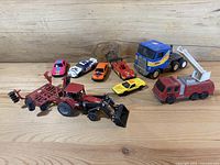 View of entire lot showing all eight toy vehicles arranged on wooden surface