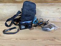 Nikon Coolpix S4200 camera with carrying case, cables, and tripod arranged on wood surface