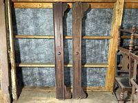 Pair of full-length wooden bed rails with carved details leaning upright against a wall, showing overall dimensions and condition.