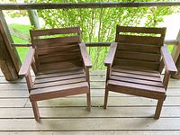 Pair of weathered wooden deck chairs on wooden porch floor, showing front and top views.