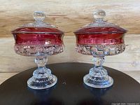 Pair of vintage lidded compotes with ruby flash and clear glass thumbprint pattern on pedestal bases