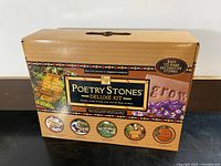 Front and sides of the Poetry Stones Deluxe Kit box showing branding, product name, and promotional images of custom decorative stones for garden use.
