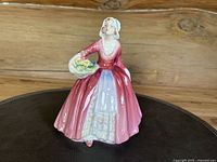 Front angle view of Royal Doulton Janet figurine, showing full gown and floral basket.