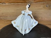 Front view of Royal Doulton 'Kate' figurine showing floral decorated white gown and figure's posture.