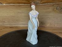 Front view of Royal Doulton figurine Linda in pale lavender gown against wooden background.