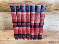 Seven hardcover volumes standing in a row showing the titles and detailed spine design with tools and home images in gold and red on black background.