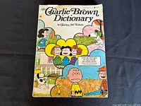 Front cover of The Charlie Brown Dictionary by Charles M. Schulz showing colorful Peanuts characters and title.