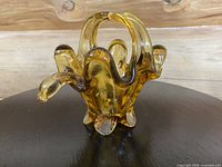 Front angle view of amber art glass basket showing curved edges, handle, and textured feet