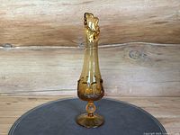 Front view of the amber swung glass vase with visible applied drip detailing and clear pedestal base.