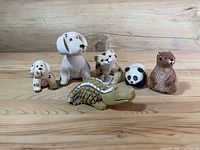 Group photo of six Rinconada ceramic animal figurines on wood surface: two dogs, cat, panda, otter, alligator.