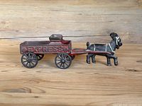 Side view of cast iron black goat pulling red express wagon with "EXPRESS" embossed on side, showing wheels and goat detail.
