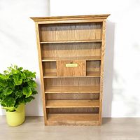 Front view of the vintage solid wood bookshelf showing all shelves and the donation box in the middle shelf area.