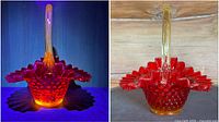 Vintage Fenton Amberina hobnail glass basket lit by UV light showing glowing orange hues and clear handle