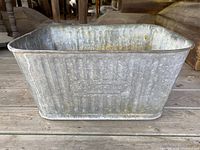 Front view of the rectangular galvanized wash tub showing ribbed sides and aged metal surface.