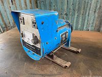 Side perspective view of the Generac 3200-watt belt-driven alternator showing blue metal housing and mounting arms.