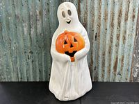 Full view of the vintage white ghost blow mold holding an orange jack-o'-lantern pumpkin. Plastic surface shows age wear.