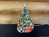 Front view of the 19-inch vintage ceramic Christmas tree showing colorful bulbs, ornaments, toys, presents at the base, and silver star topper.