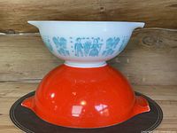 Stacked view of Butterprint 443 mixing bowl on top of Friendship 444 red mixing bowl showing exterior designs and pour spouts.