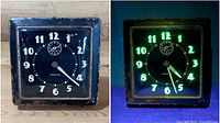 Front view of the Westclox clock under UV light highlighting the glowing radium paint on numerals and hands.