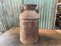 Front view of vintage metal milk can showing overall shape and embossed "WESTERN DAIRY" text with rust patina.