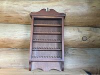 Front view of wooden thimble display cabinet without door, showing the five shelves with individual slots for holding thimbles securely in place.