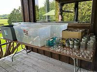 Full view of canning jars, lids, rings, and storage totes on table showing assortment and quantities.
